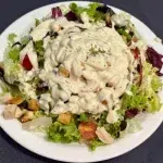 Ensalada de hojas verdes con pollo asado, tomates cherry y salsa de yogur