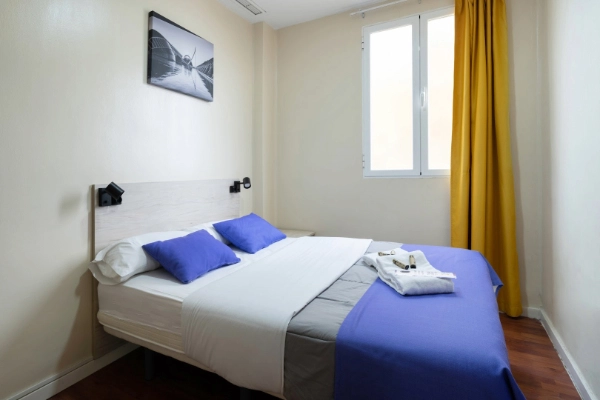 Habitación doble con cama de matrimonio y decoración moderna, ideal para despedidas de soltera en Valencia.