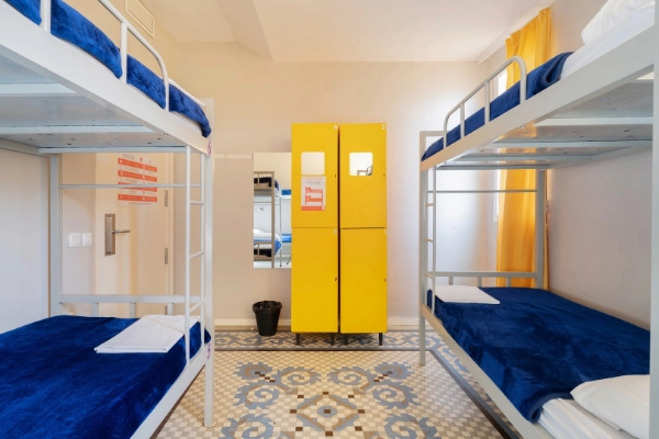 Habitación con literas azules y taquillas amarillas en alojamiento para grupos en Valencia.