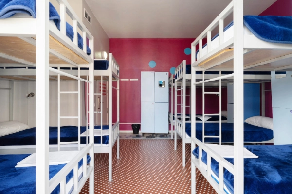 Dormitorio amplio con literas blancas y pared rosa decorativa.