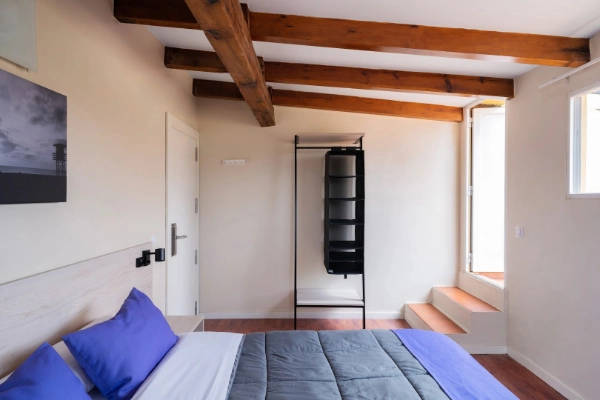 Habitación acogedora con techos de vigas de madera y cama doble para despedidas de soltera en Valencia.