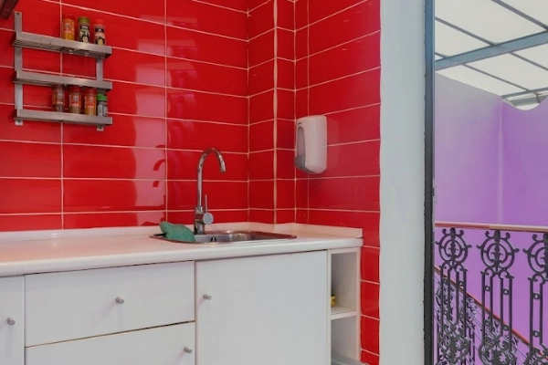 Lavabo de cocina en alojamiento turístico con azulejos rojos y acceso a balcón, ideal para grupos en despedidas.