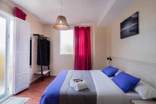 Habitación con cama doble, cortina roja y ambiente cálido para parejas o amigas en despedida.