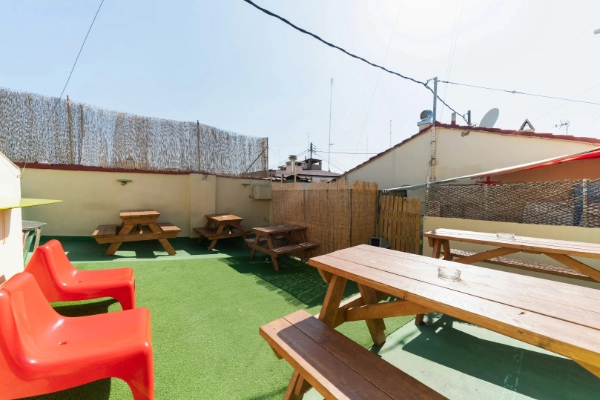 Terraza exterior con mesas de madera en el Red Nest Hostel de Valencia, ideal para grupos.