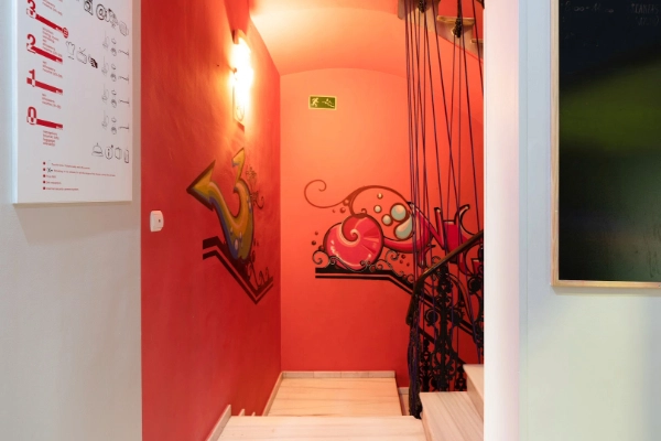 Escalera interior decorada con mural artístico en Red Nest Hostel, Valencia.
