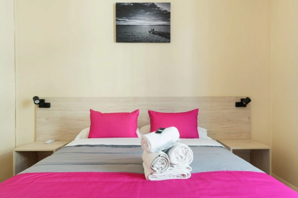 Camas individuales con almohadas color fucsia en habitación del Red Nest Hostel.