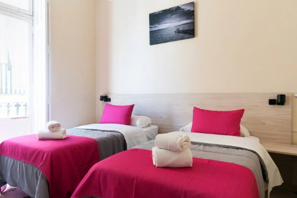 Habitación doble con camas individuales y decoración moderna en el Red Nest Hostel Valencia.