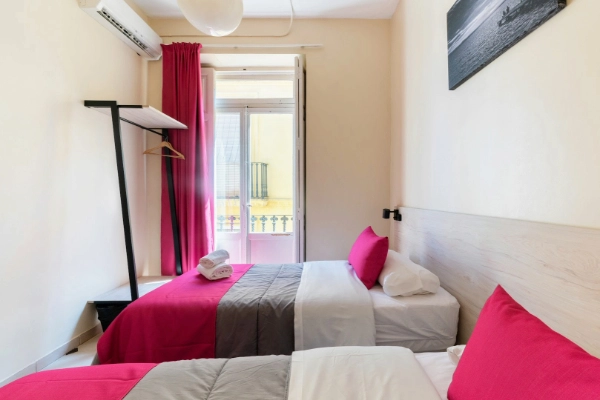 Habitación doble con balcón exterior y decoración moderna en el Red Nest Hostel Valencia.