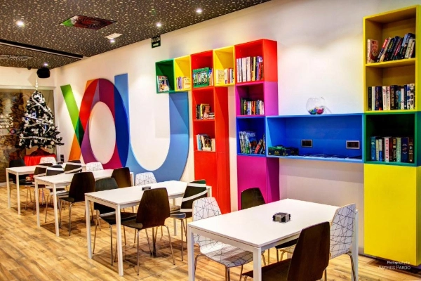 Zona de lectura o coworking en el Hostel Urban Youth Valencia con estanterías coloridas.
