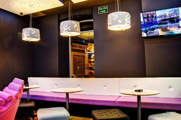 Zona de comedor interior con sofás y lámparas colgantes en el Hostel Urban Youth de Valencia.