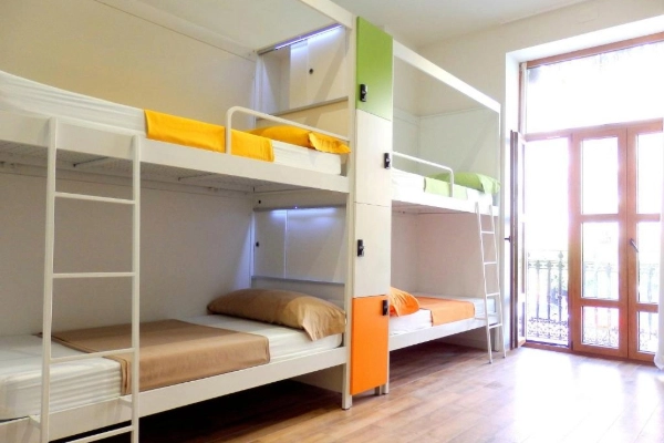 Literas modernas en habitación compartida del Hostel Urban Youth en Valencia con luz natural y taquillas de colores.
