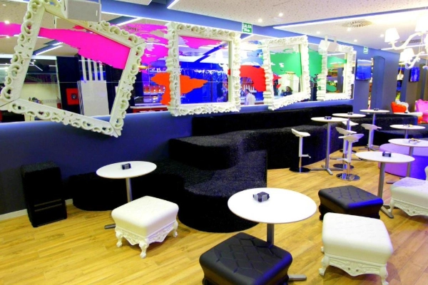 Zona lounge con sofás negros curvos y espejos de diseño en el Hostel Urban Youth.