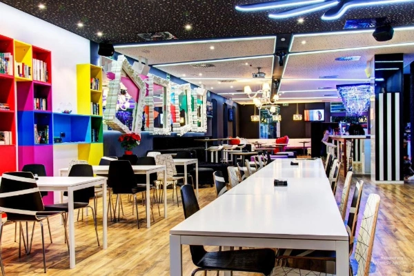 Sala común del Hostel Urban Youth con decoración moderna y mesas largas.