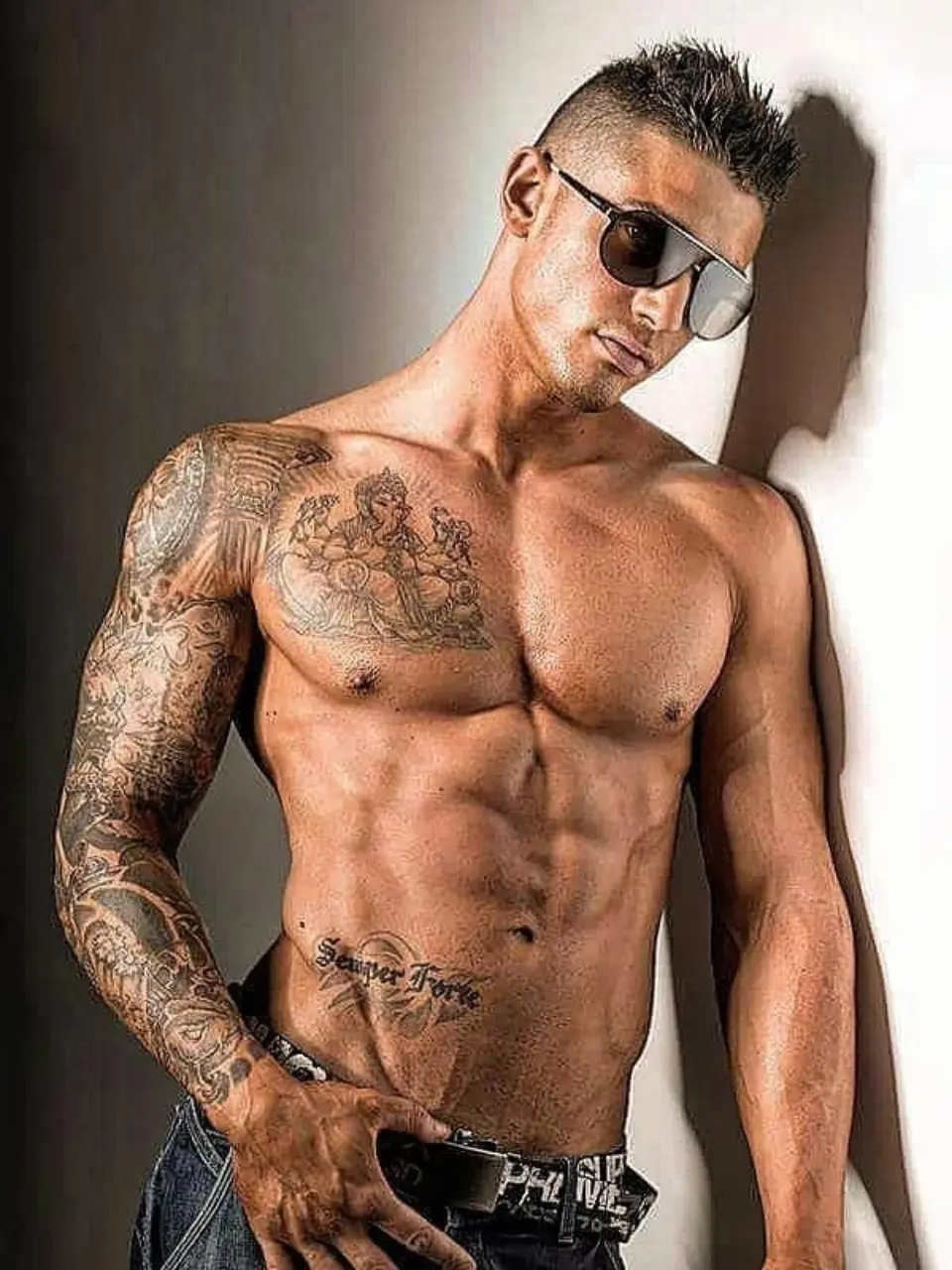 stripper boy en valencia posando sin camiseta con tatuajes y gafas de sol
