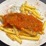 Lomo de merluza con salsa de tomate y pimientos acompañado de patatas fritas