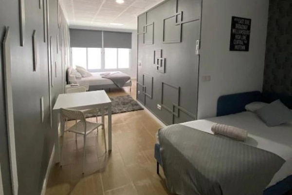 Habitación moderna con camas y mesa en hostal de Poblados Marítimos en Valencia